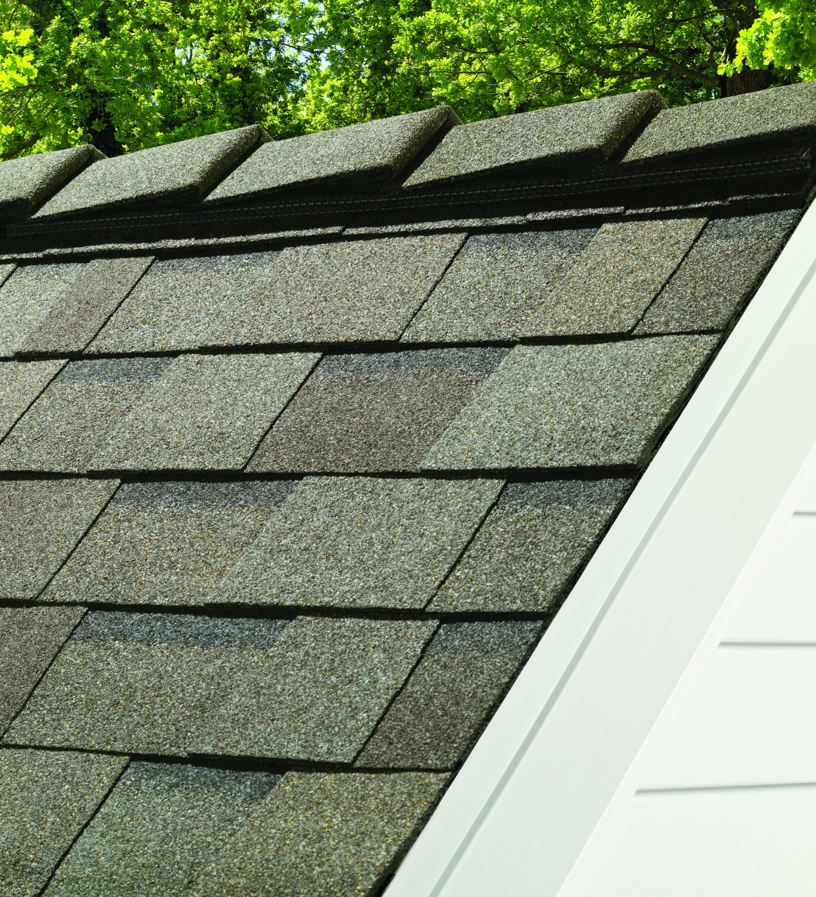 Gray architectural asphalt shingle roof with a dormer window on a sunny day.